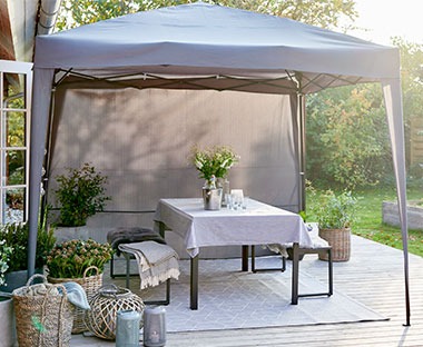 Tonnelle en gris sur une terrasse avec une table et des bancs