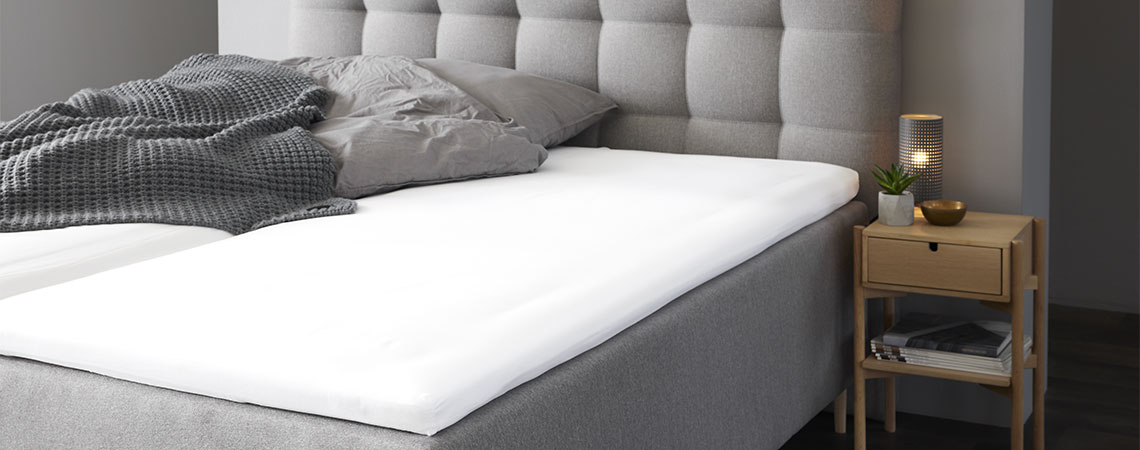 Slaapkamer met grijs kingsize bed met dekmatras en grijs hoofdkussen en dekbed