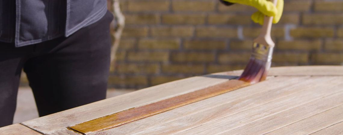 Persoon die toont hoe je je houten tuinmeubelen onderhoudt
