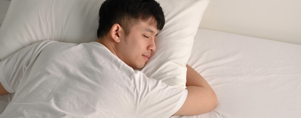 Geniet elke nacht van een goede nachtrust met een dekmatras die goed op zijn plaats blijft Man die vredig in bed slaapt, met een wit kussen en een witte dekmatras