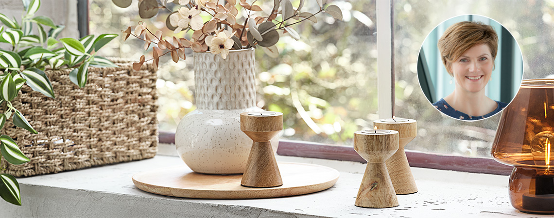 Lampe, photophores, vase blanc et panier avec plante sur un rebord de fenêtre