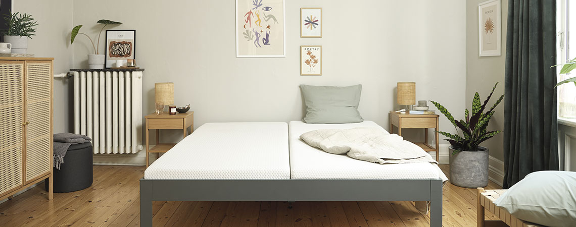 Tweepersoonsbed met grijs bedframe en matras en nachtkastjes