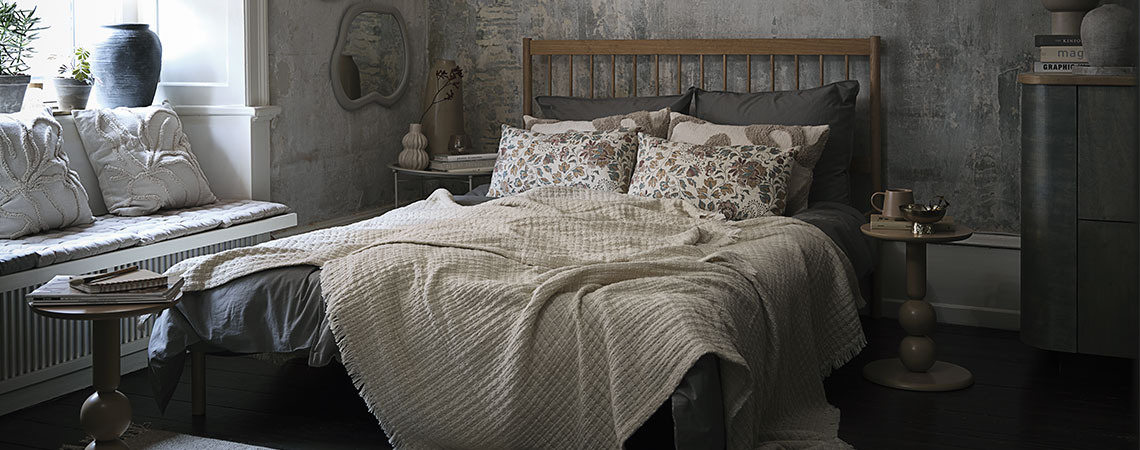 Bed met kussens en plaids in beige en groene tinten