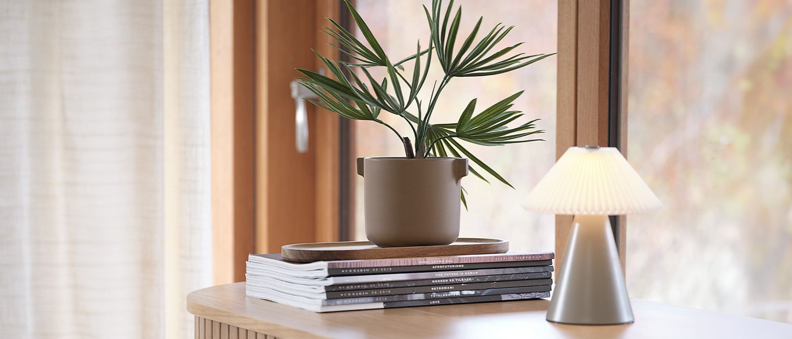 Voeg een vleugje onderhoudsvrij groen toe aan je huis Kunstplant in een bloempot op een bureau met boeken en een tafellamp