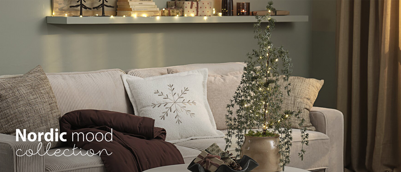 Coussin SANDSTEN avec un flocon de neige, couverture SKOGSTRY matelassée et sapin de Noël artificiel GRENDAL Canapé avec des coussins et plaids dans une salon décoré pour Noël