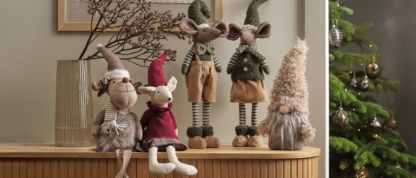 Les lutins et les souris de Noël scandinaves sont des compagnons incontournables des fêtes de fin d’année. Lutins barbus, lutins de Noël et souris décoratives sur un buffet, avec un sapin de Noël en arrière-plan.