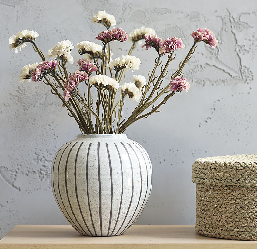 Roze en witte kunstbloemen in witte vaas met grijs streeppatroon