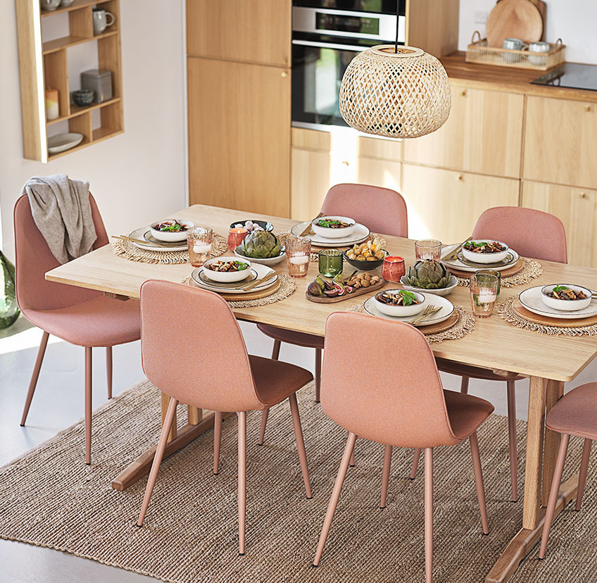 Zachte perzikkleurige eetkamerstoelen rond een tafel in een keuken