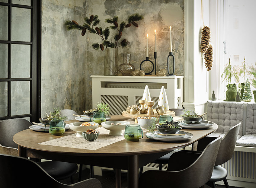 Salle à manger avec table dressée avec chemin de table de Noël, assiettes, plats et décorations de Noël