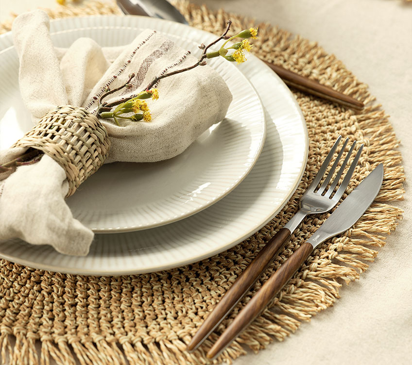 Couverts REMI, assiettes en grès cannelé STEFFEN, serviette en tissu KASTANIE et set de table LIND Table entièrement dressée avec serviette en tissu, assiettes en grès et couverts avec poignées.