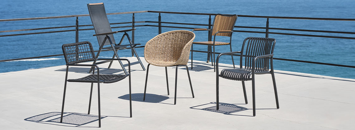 A selection of five garden chairs on patio byEen selectie van vijf tuinstoelen op patio aan zee the sea