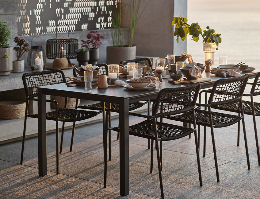 Tuintafel en tuinstoelen met tafelset voor diner op patio bij zonsondergang