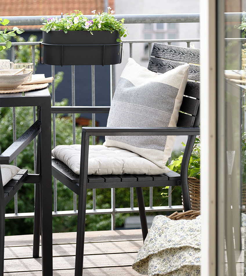 Chaise de jardin empilable noire avec coussins sur un balcon