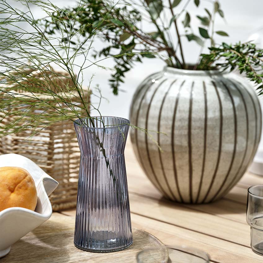 Vases, lanternes et bol sur une table de jardin en bois en extérieur