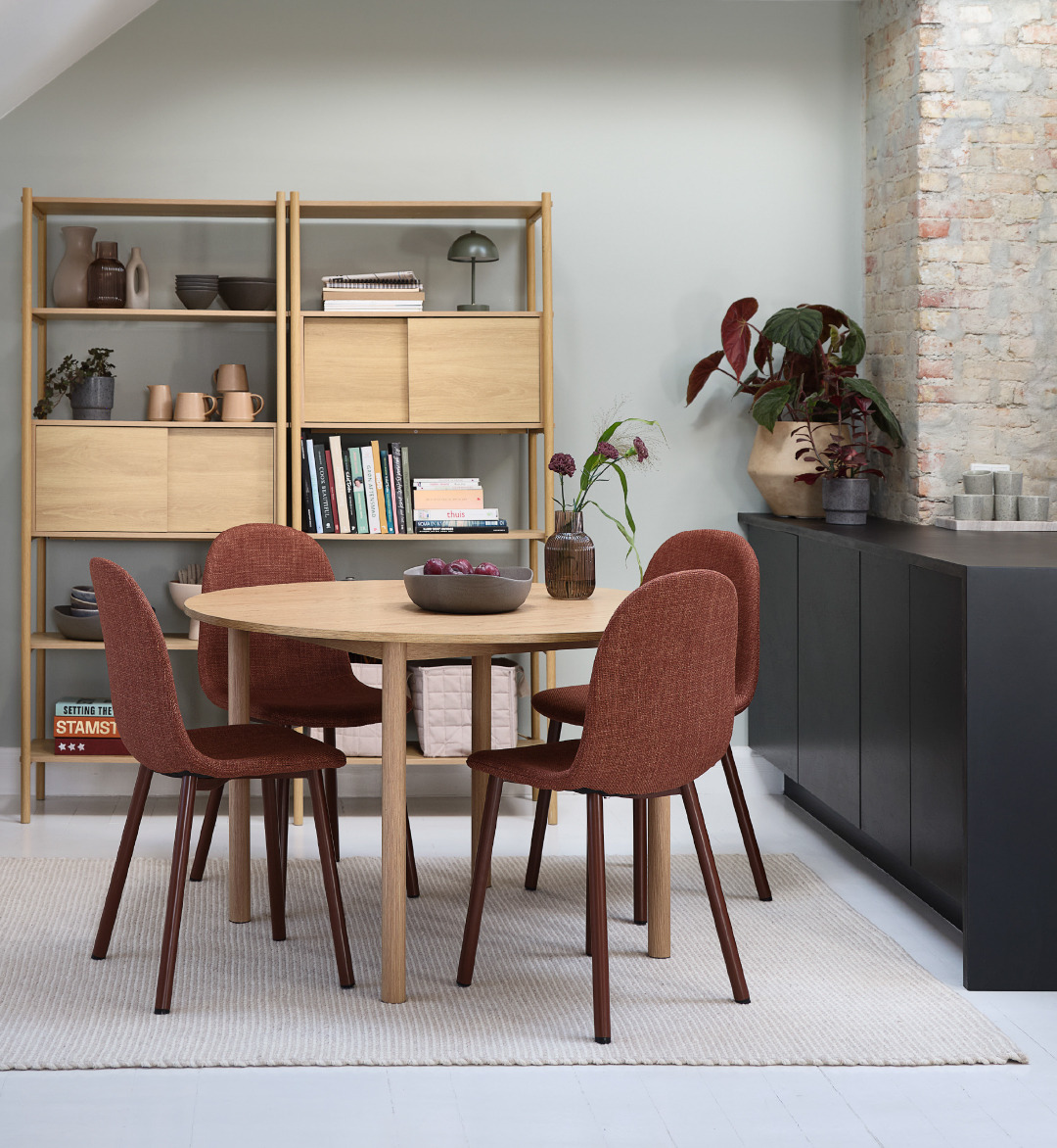 Salle à manger avec table ronde et chaises terracotta et bibliothèques