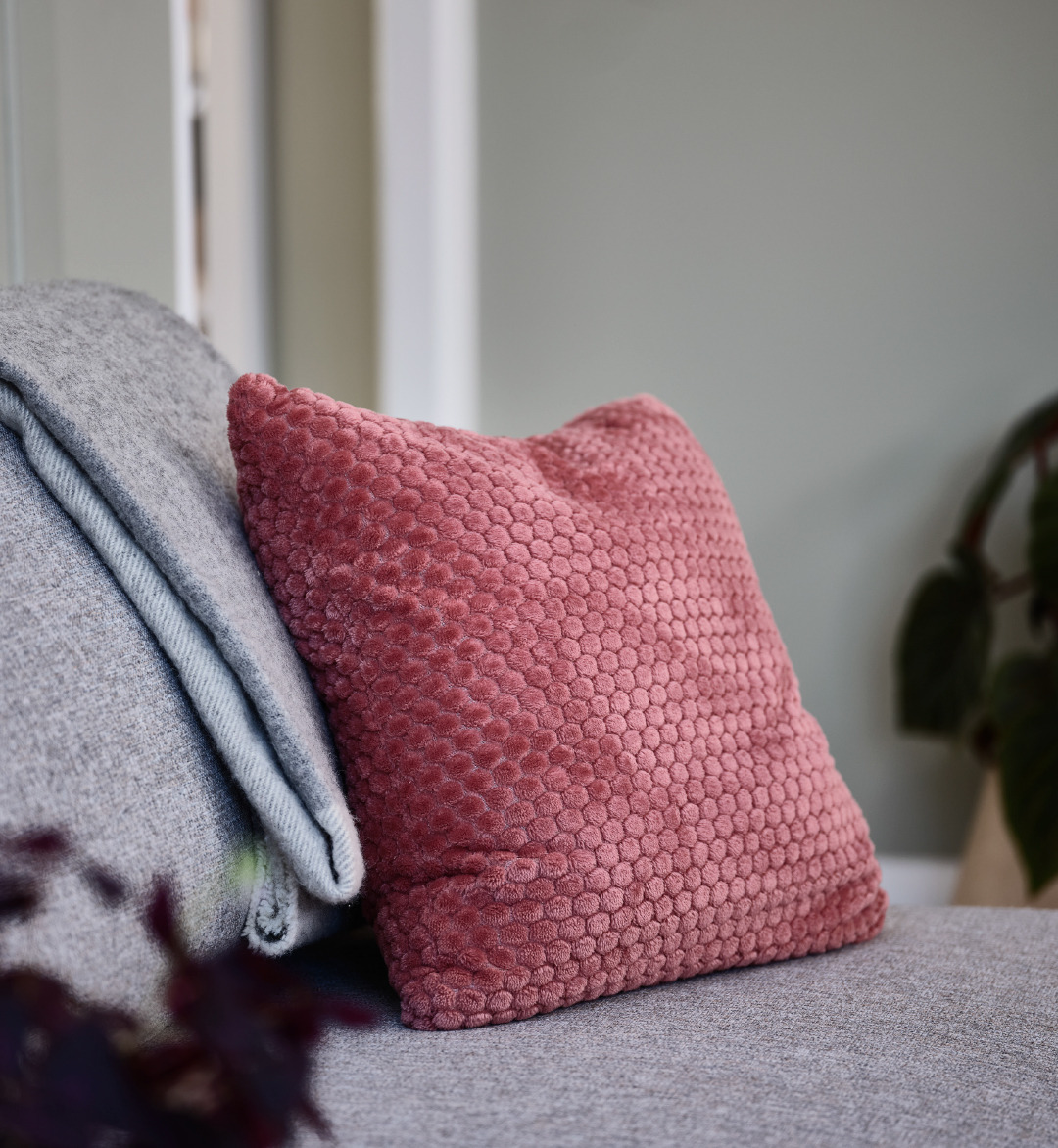 Coussin rose sur un canapé convertible gris