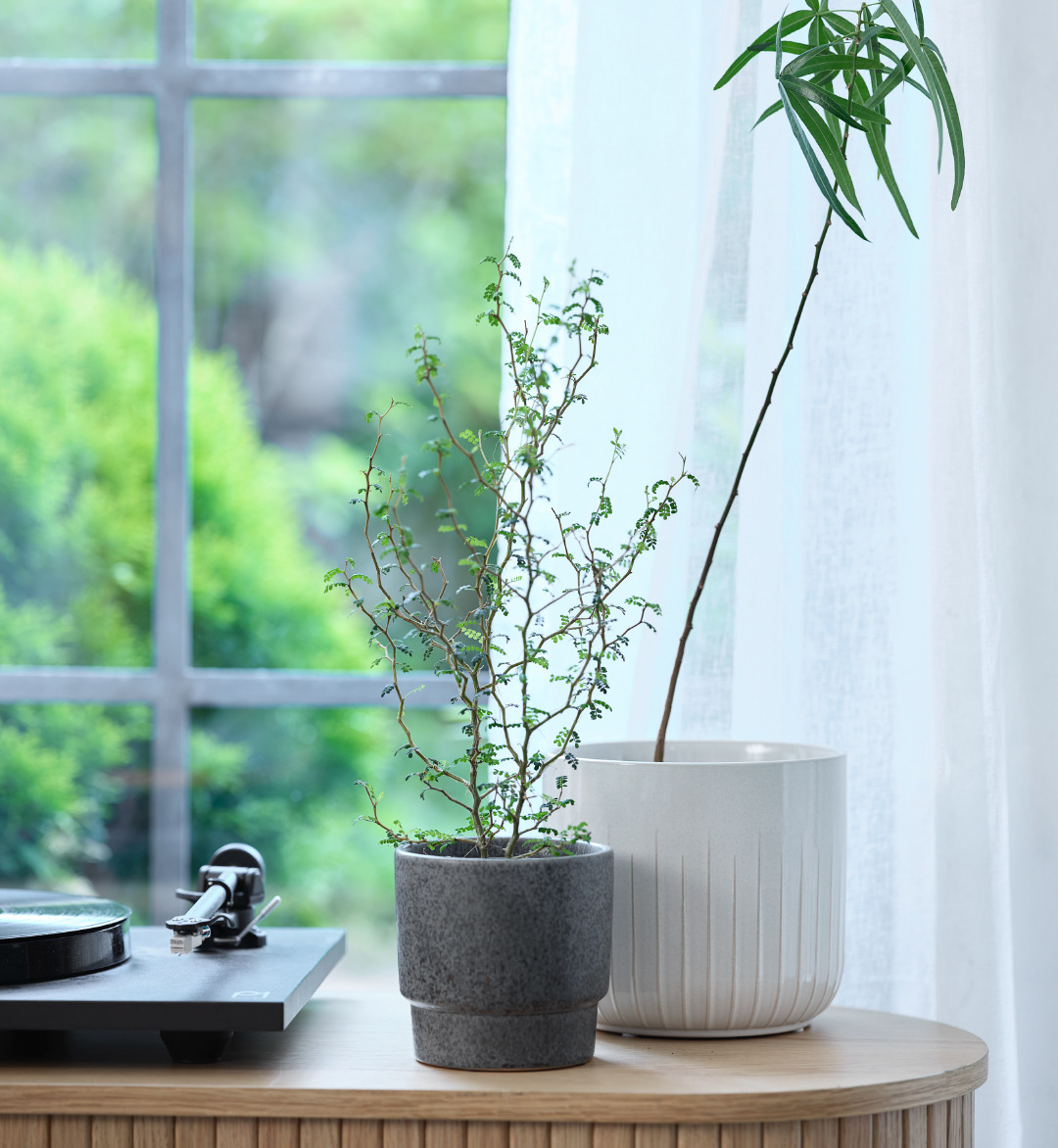 Twee bloempotten met kunstplanten op een dressoir