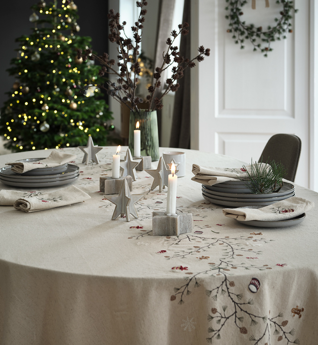 Table de Noël joliment décorée avec une nappe de Noël brodée