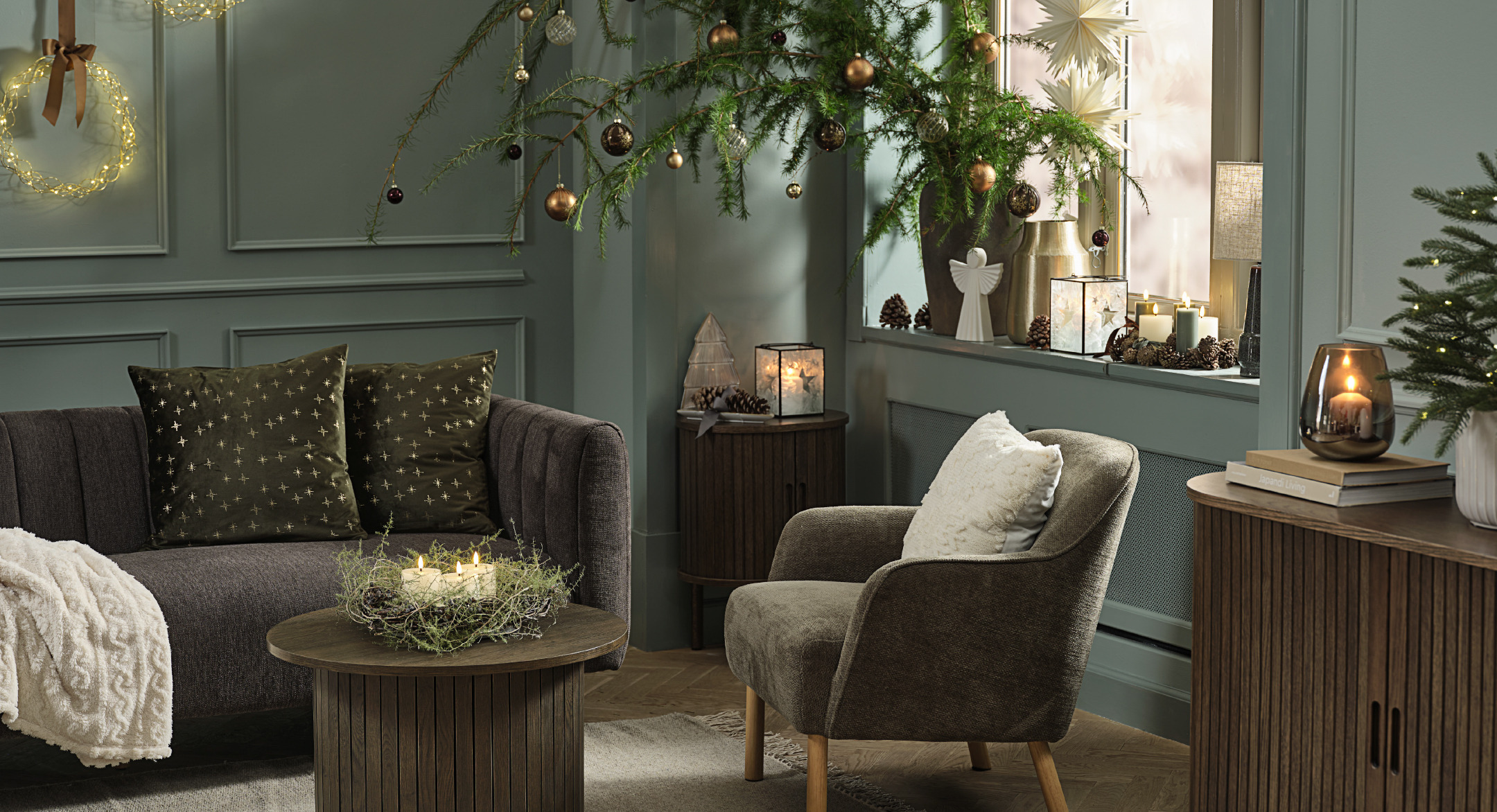 Kerstkrans SNE, groen kussen ALVALDE, kussen wit NJORD, kaarsen GALAR, dressoir LYNGVIG Gedecoreerde woonkamer met kersttexiel, kerstbomen, takken en decoratie