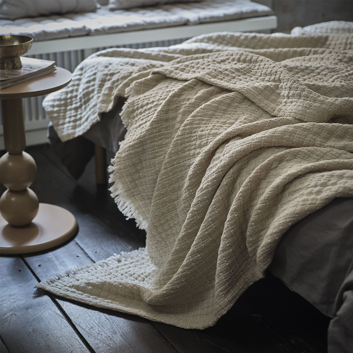 Beige plaid op een bed in een slaapkamer