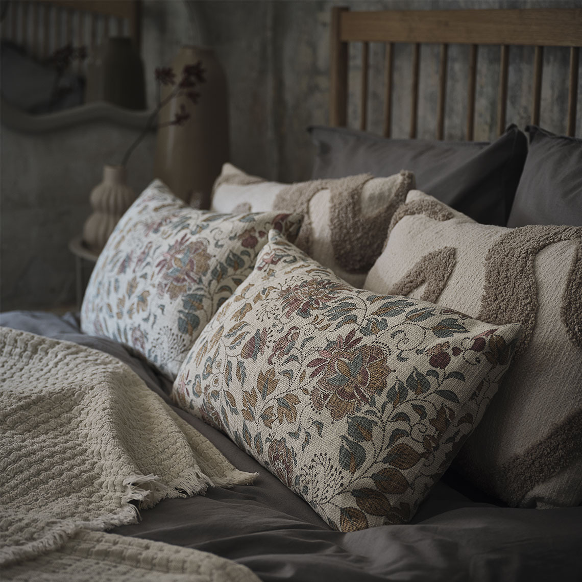 Kussens met bloemenprint en beige kussens in een bed met een beige plaid