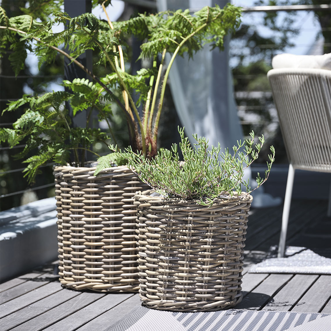 Twee plantenmanden van natuurlijk, onbehandeld rotan op een balkon met planten
