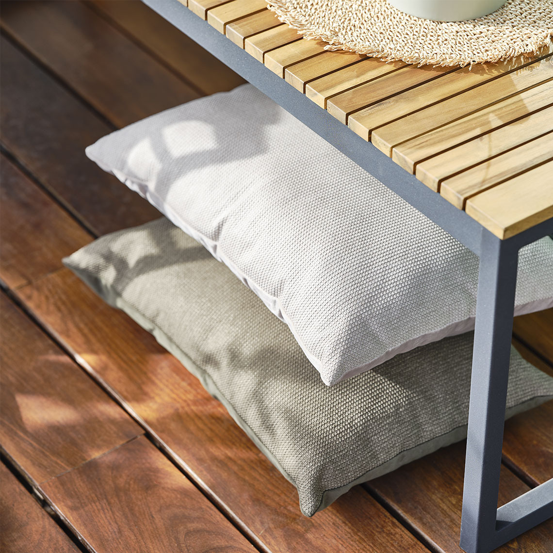 Beige kussens onder een tuinbank