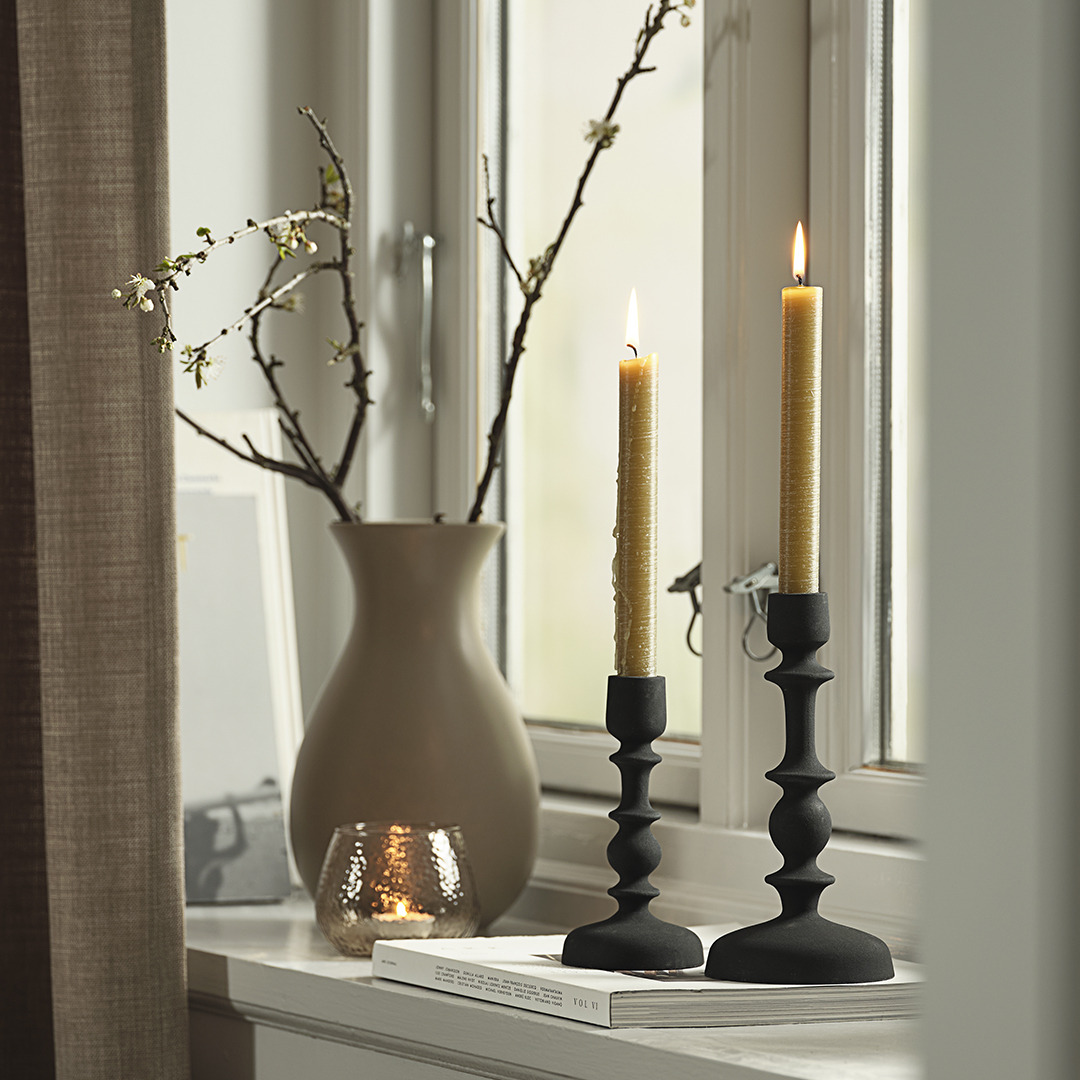 Vase et chandeliers avec bougies à mèche sur le rebord d'une fenêtre