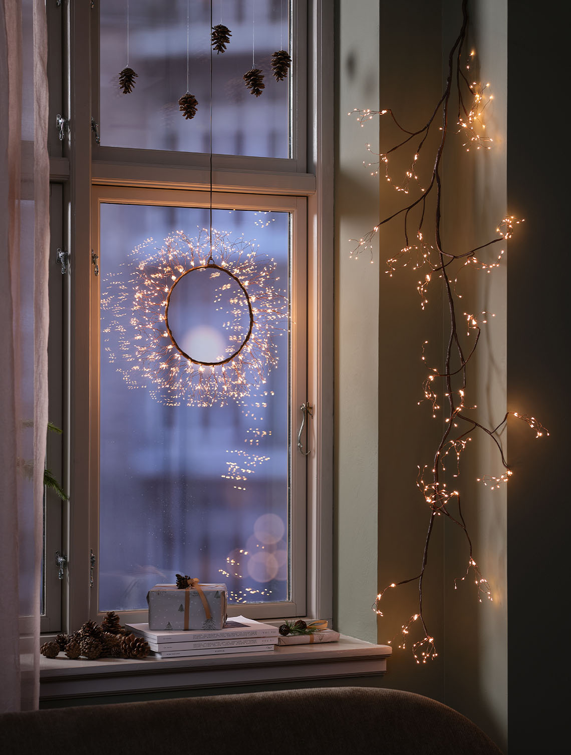 Kerstkrans die een raam binnen in huis verlicht.