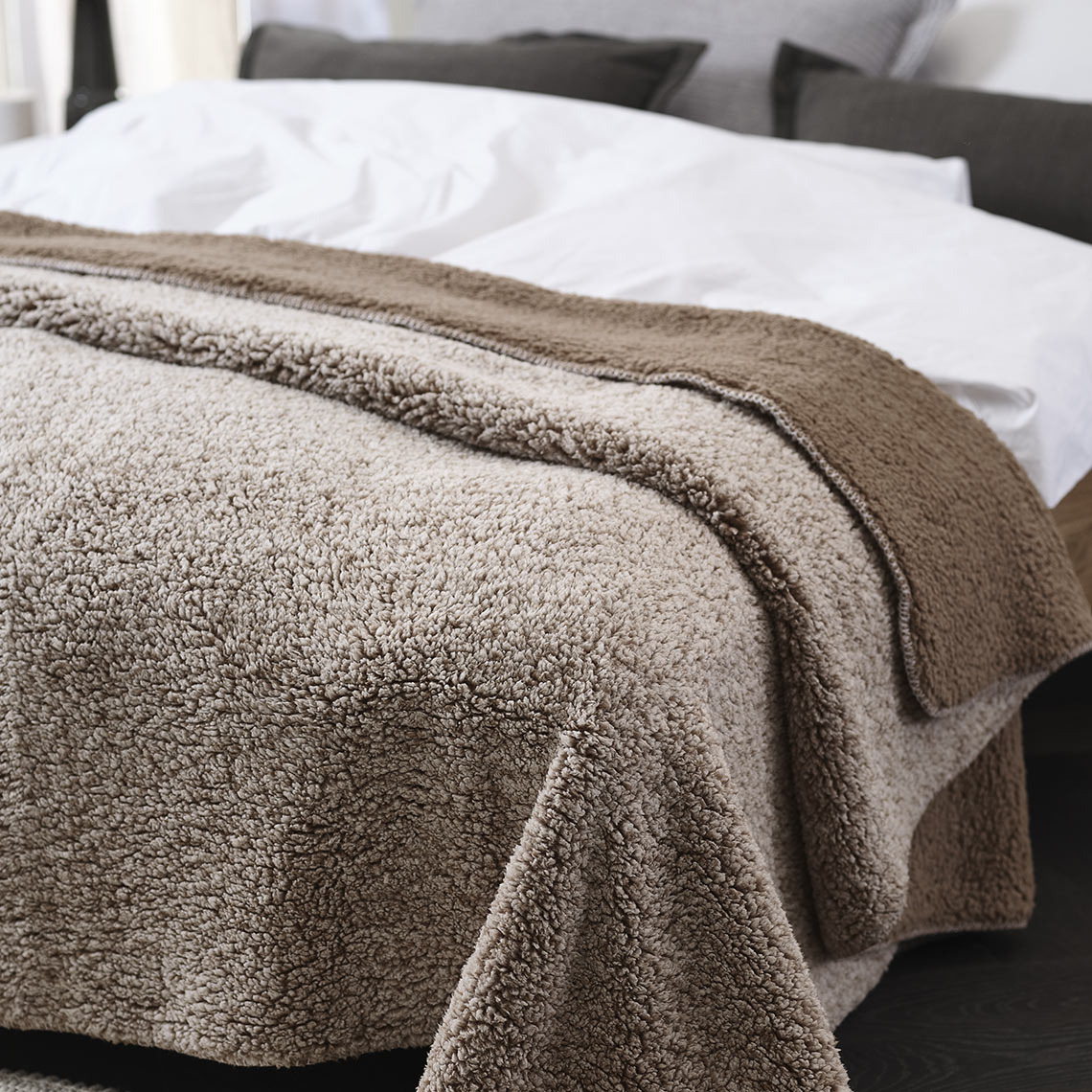 STORFRYTLE fleecedeken Bruine fleecedeken op een bed in de slaapkamer