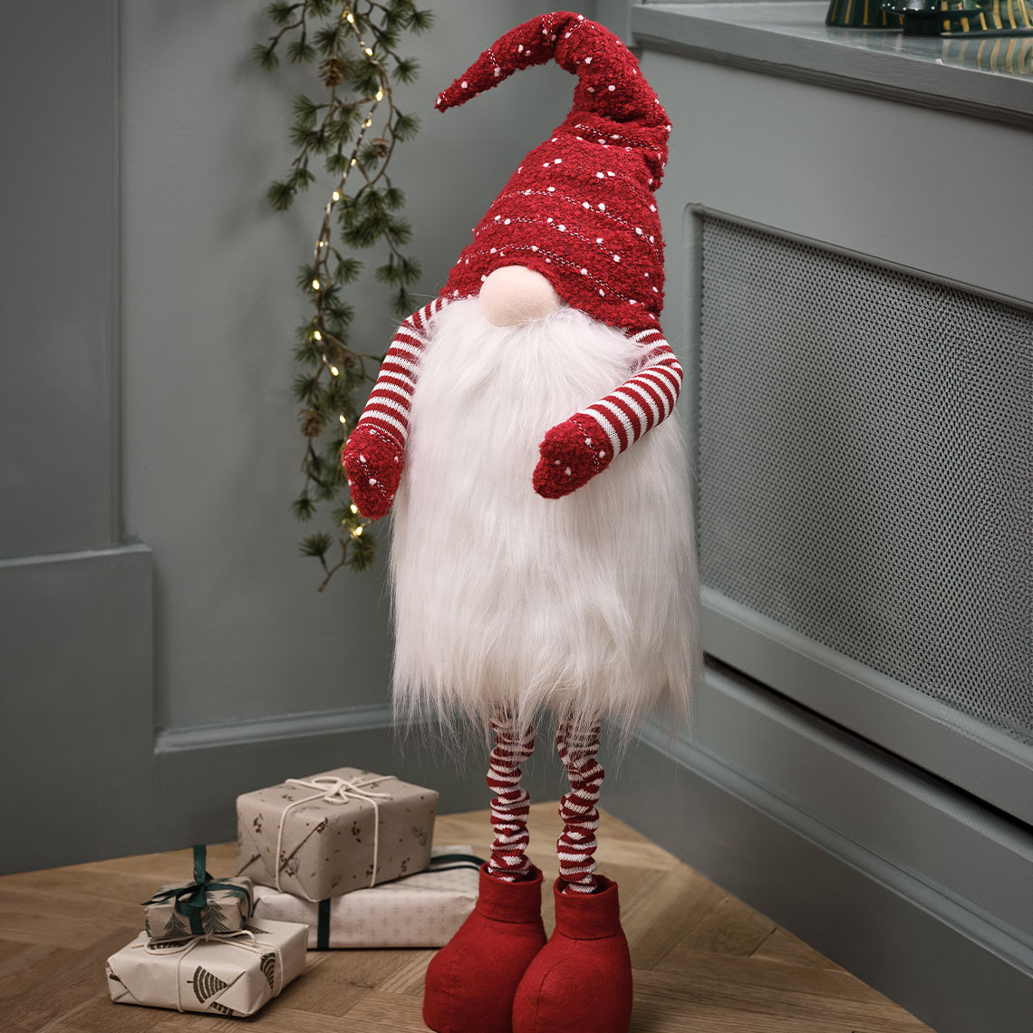 Grand lutin de Noël avec un bonnet rouge et une longue barbe à côté d’une lanterne noire en forme d’étoile