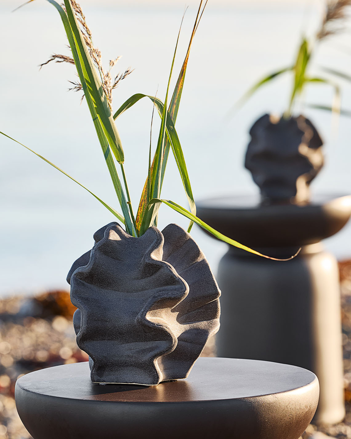 Organische vorm vaas op pedestal op een strand