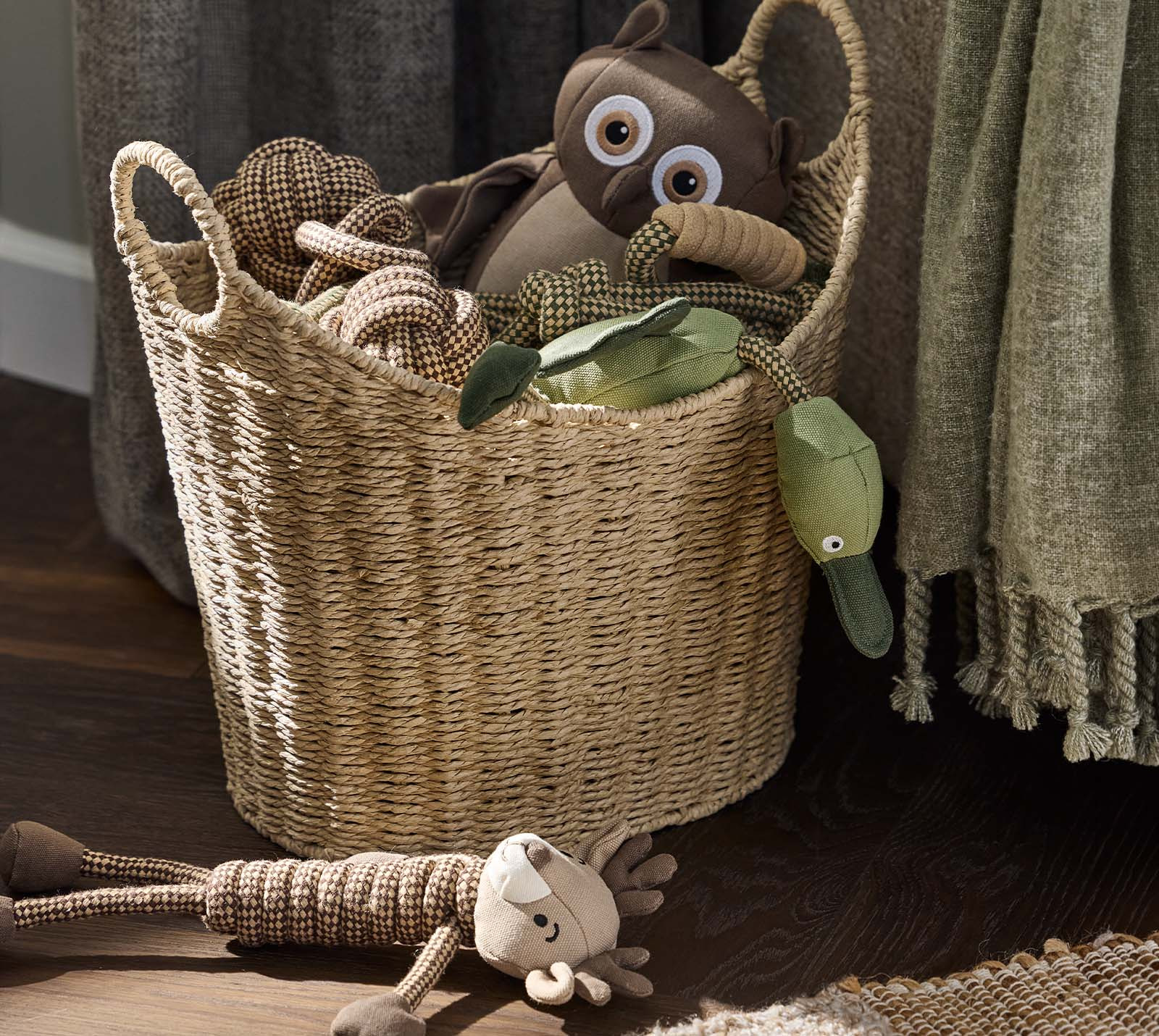 Jouets pour chien fabriqués en différents textiles, dans un panier dans le salon