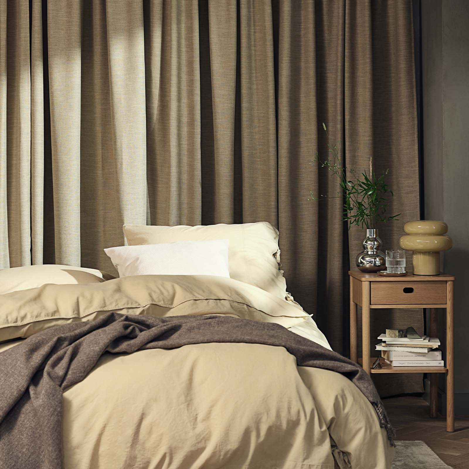 Slaapkamer met een groot, zwaar gordijn in de kleur kaki