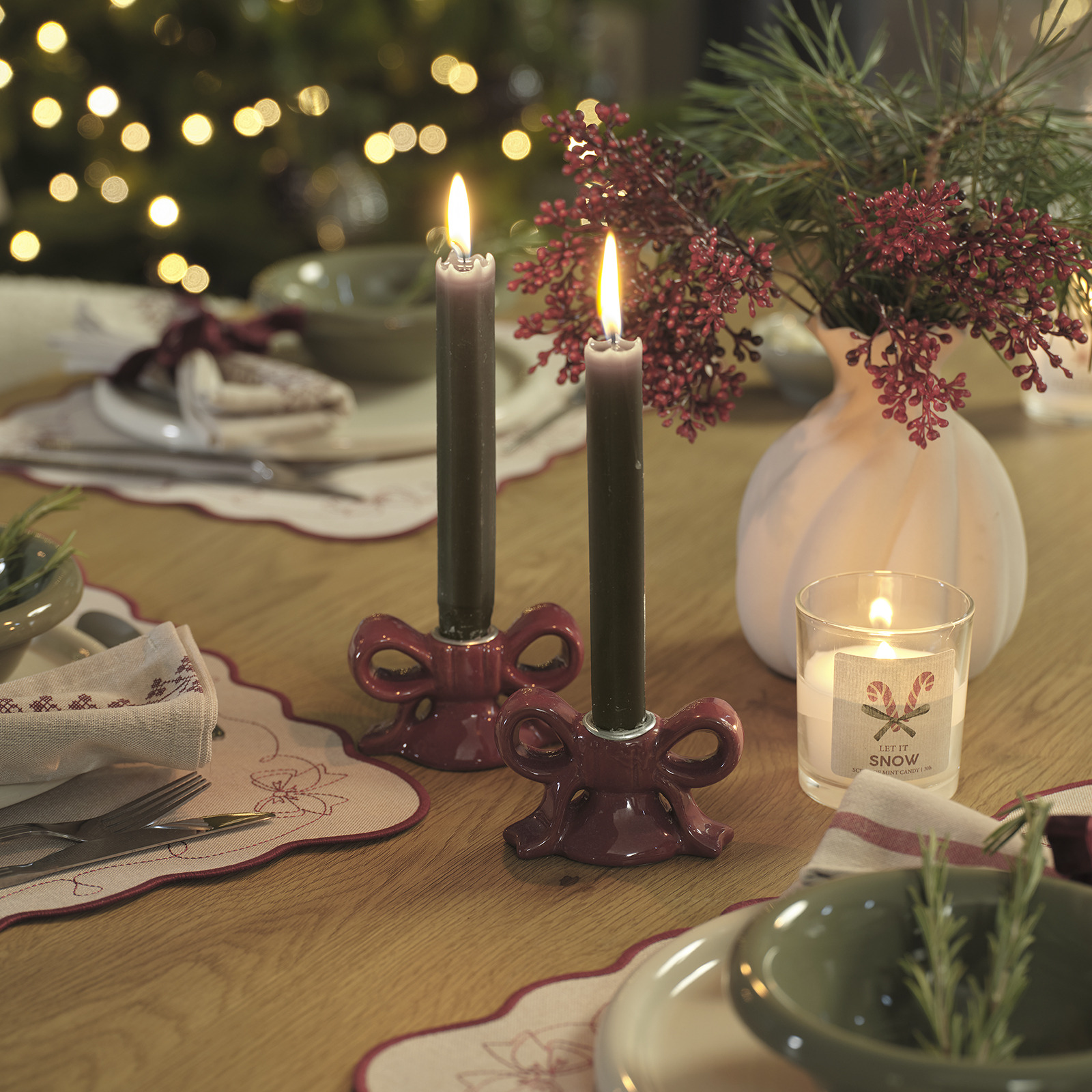 Table de Noël décorée d’un vase de fleurs artificielles et de bougeoirs avec des bougies
