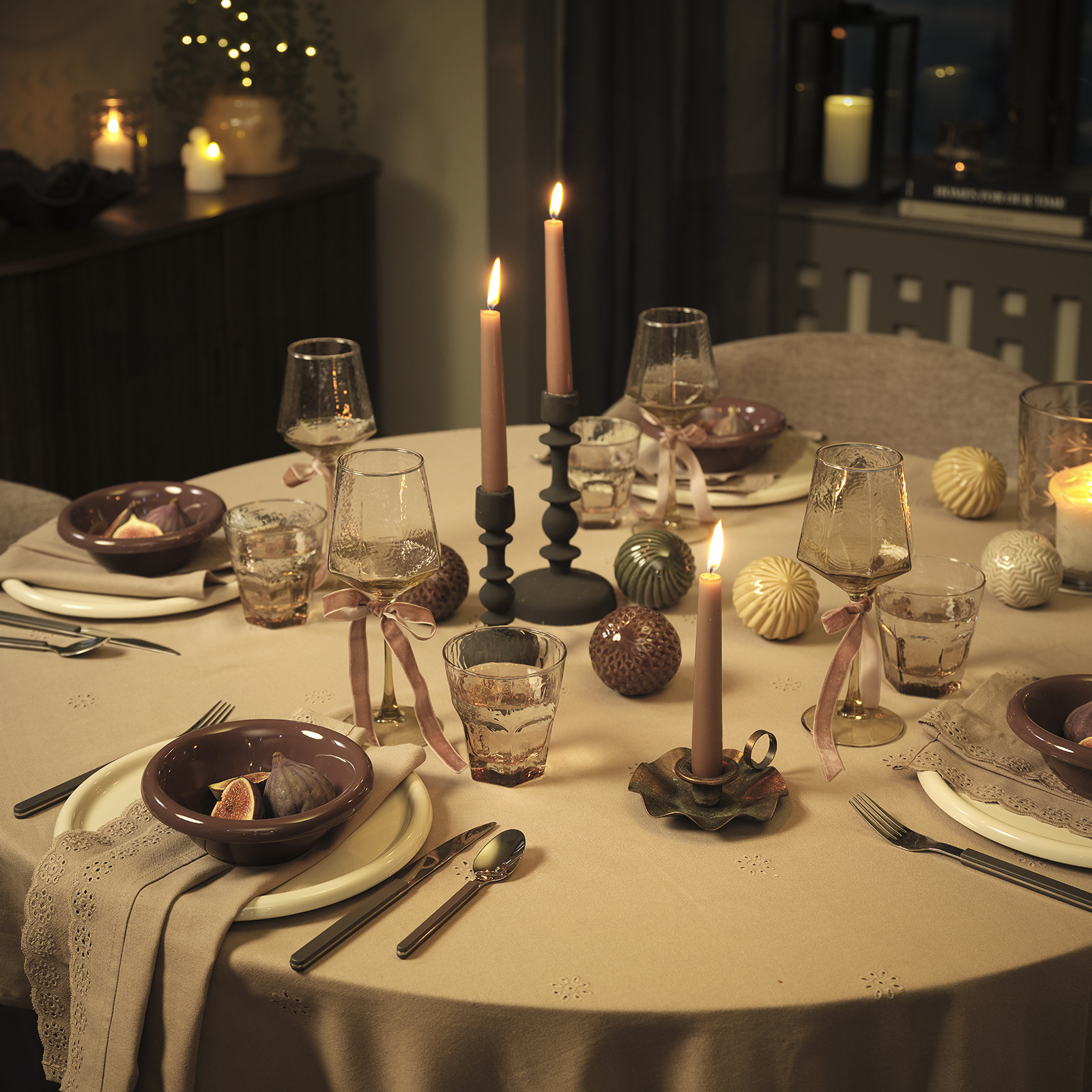 Table de Noël éclairée à la bougie, dressée avec des assiettes, des bols, des couverts et des décorations