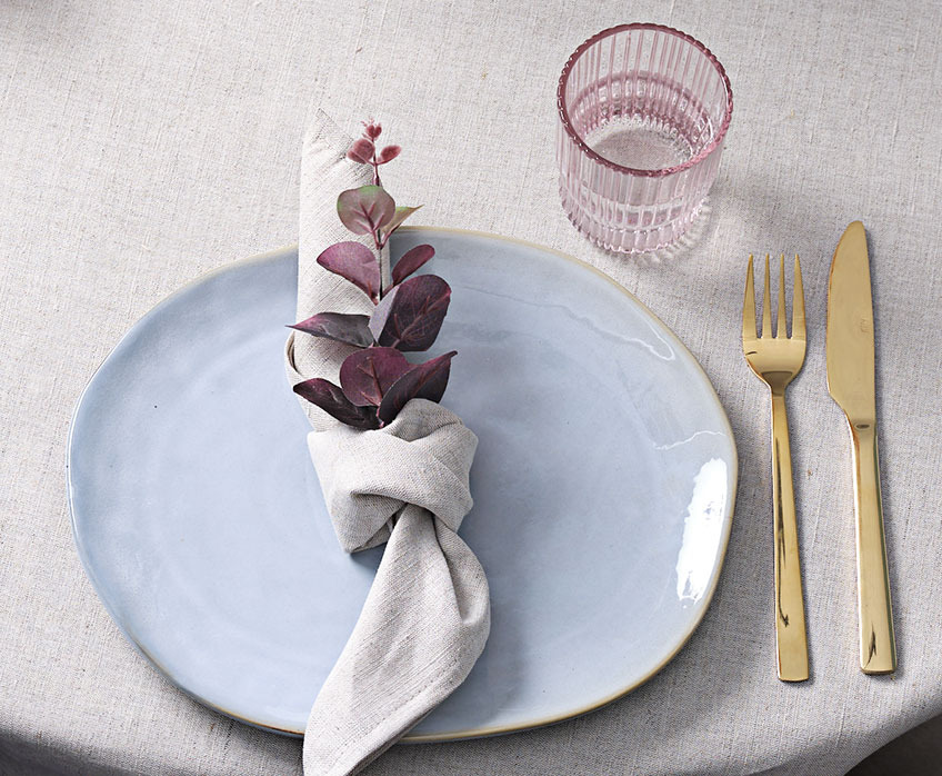 Decoratieve tafelsetting met bord, linnen servet, glas en mes en vork