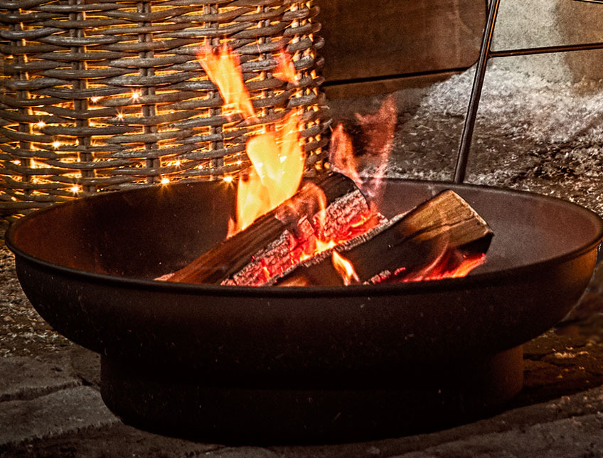 Outdoor fire pit with burning logs on a patio