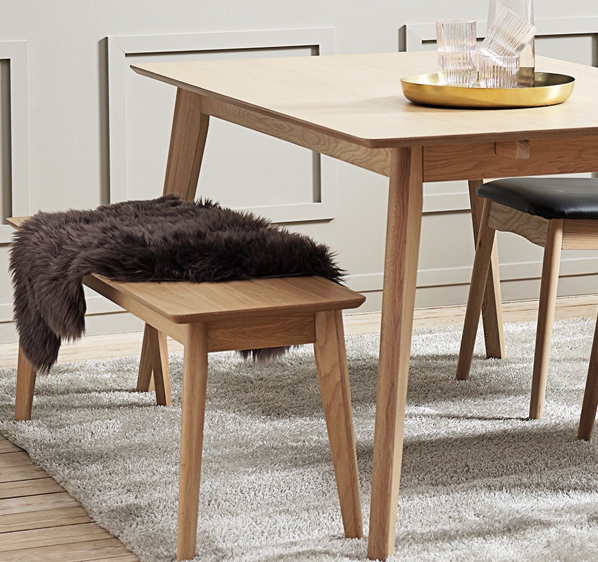Drie mensen kunnen gemakkelijk bij elkaar zitten op de KALBY eetbank. Een bank in de eetkamer, half bedekt met een huid, aan een eettafel.