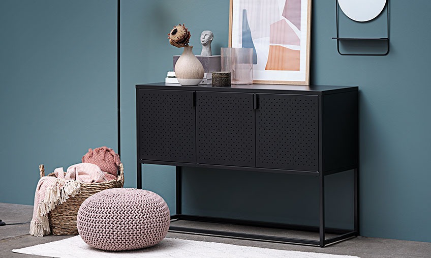 Knitted footstool in front of a sideboard with a vase and other knick knack