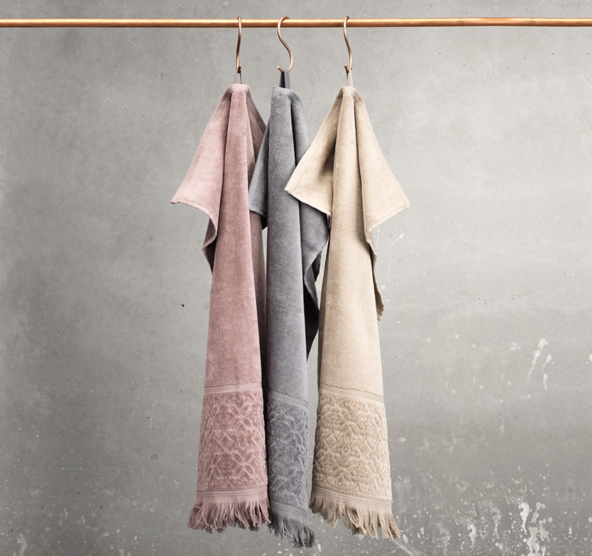 SVANESUND towels in 100% cotton are available in different colours Taupe, sand and grey towel hanging from a rail