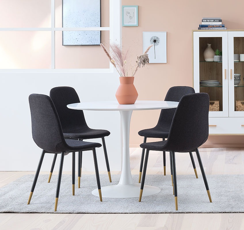 Moderne eetkamerstoelen in zwart en goud rond een witte, ronde tafel 