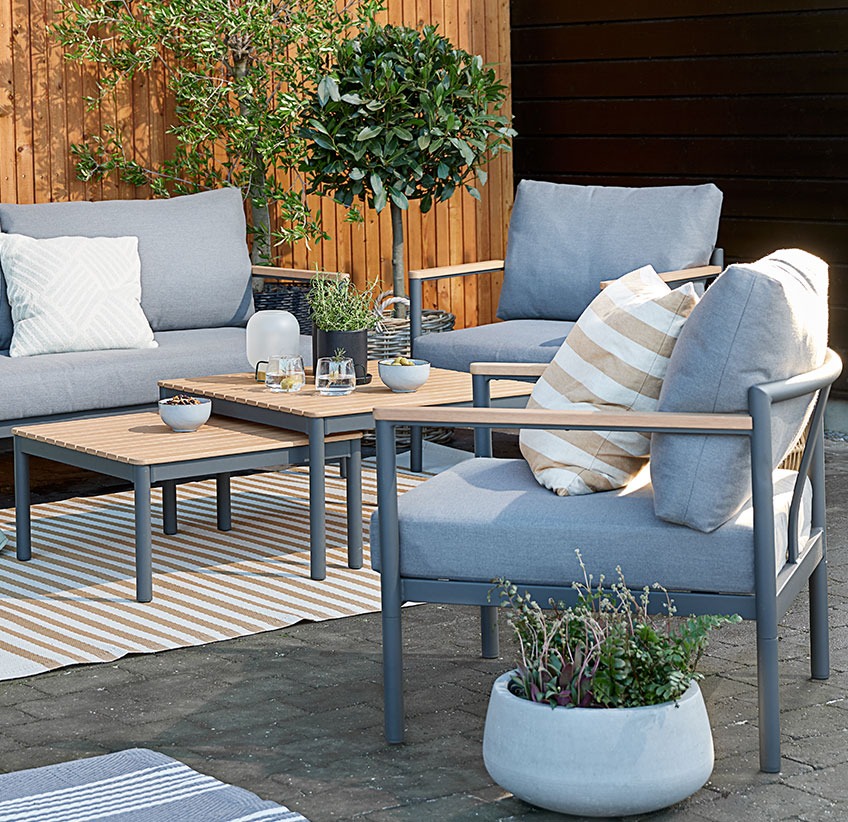 Tuin loungeset met comfortabele kussens op een patio met tapijten en plantenbakken