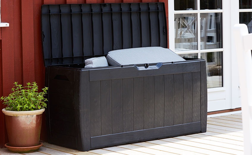 Zwarte kussenbox met open deksel op een patio