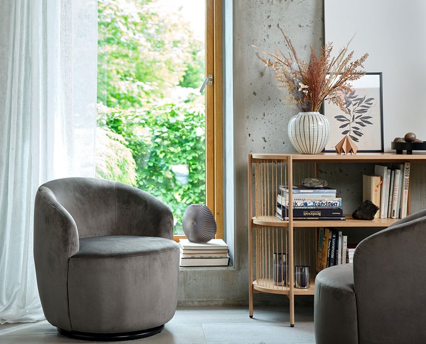 Grijze fauteuil en een dressoir met boeken en vazen