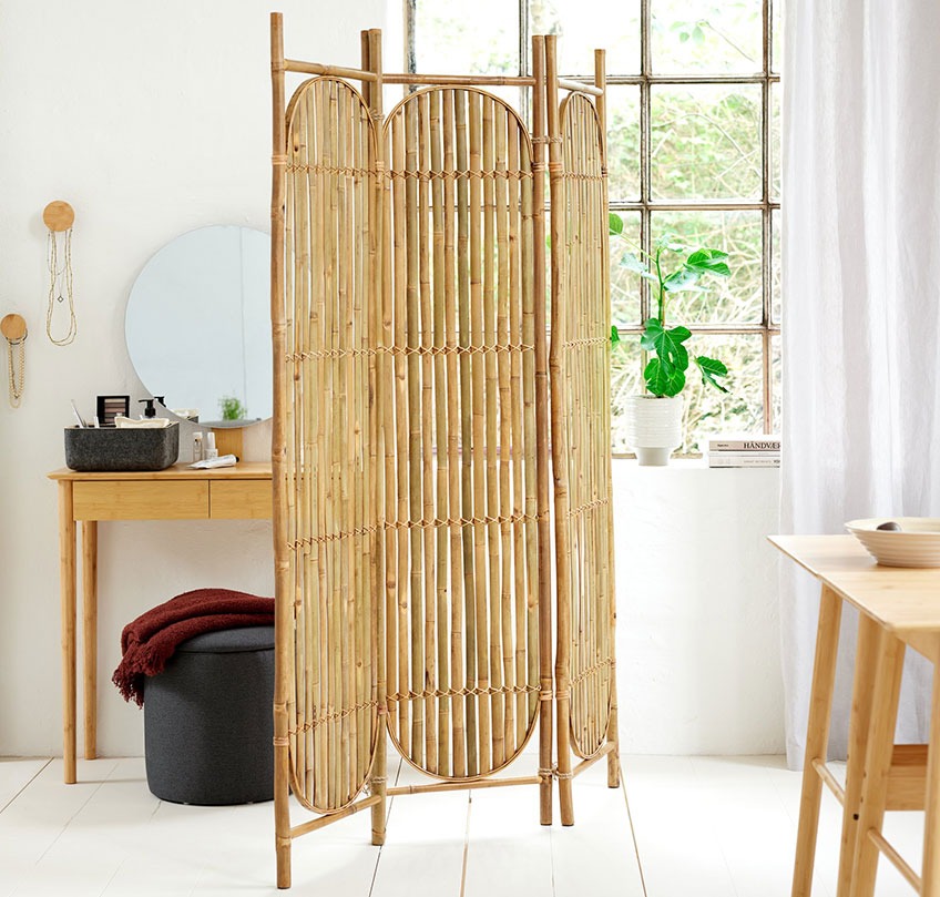 Bamboe room divider staat tussen een woon- en slaapgedeelte