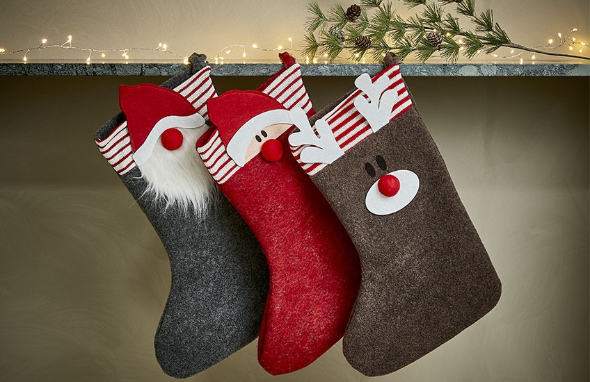Christmas stockings hanging on shelf with motive of Santa, elf, and reindeer