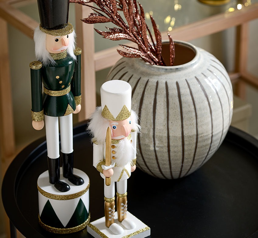 VALI en EUKLAS notenkraker figuren en SOFUS vaas op RANDERUP salontafel Twee kerstfiguren en een vaas op een zwarte salontafel