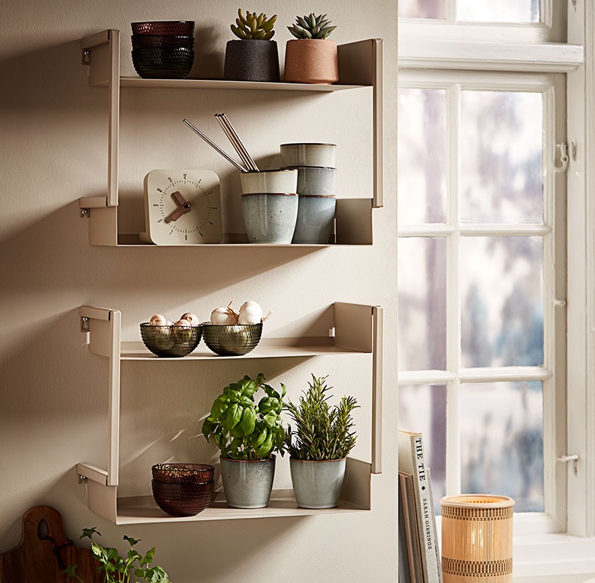 Glazen schaaltjes, mokken van steenwerk and verse kruiden op een wandplank in de keuken