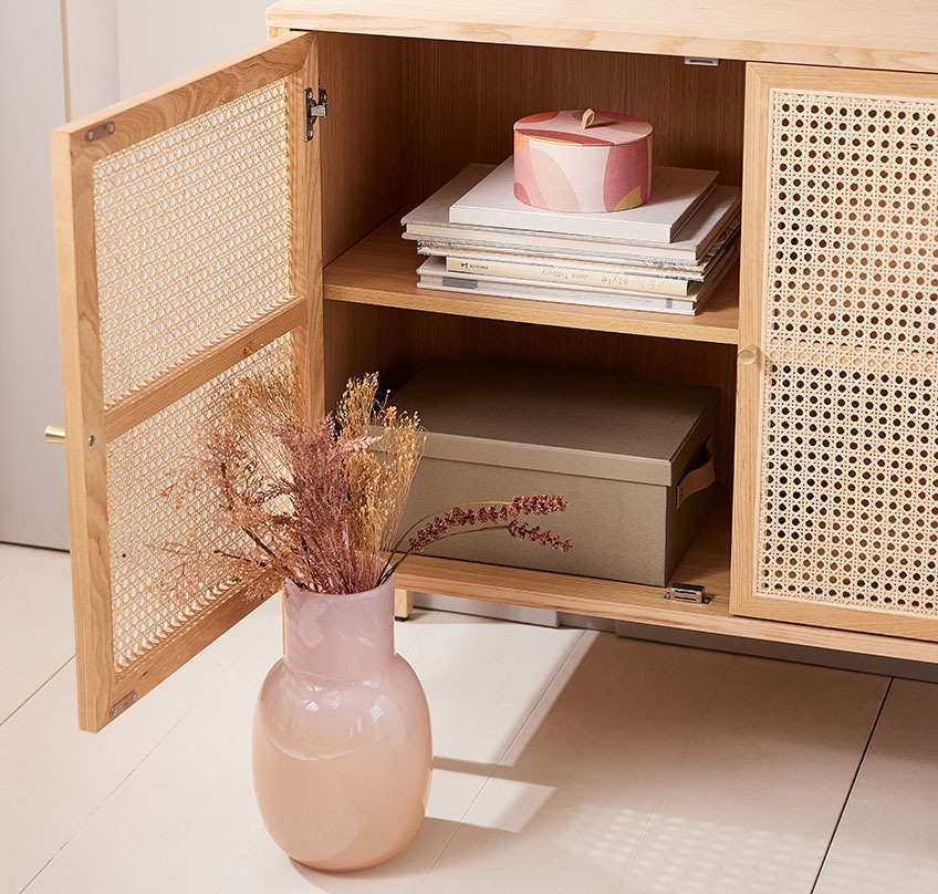 KASPER vase and round OLA storage box in SALTVIG sideboard Mouth blown vase with a bouquet of artificial flowers in front of sideboard with an open door and a round storage box inside